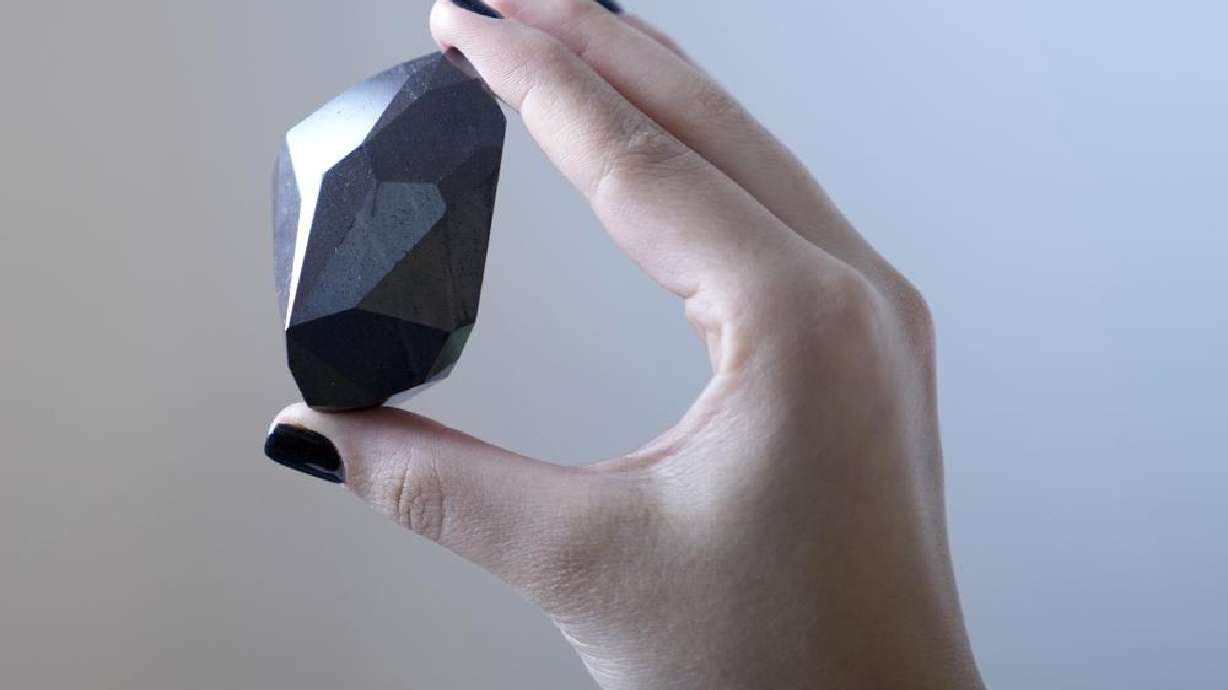 An employee of Sotheby's Dubai presents 555.55-carat black diamond "The Enigma" to be auctioned at Sotheby's Dubai gallery, in Dubai, United Arab Emirates, Monday.