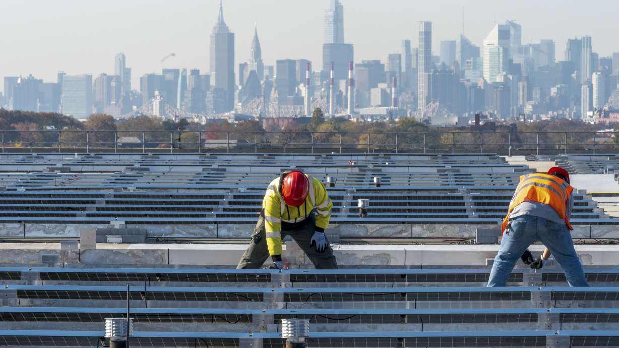 Framed by the Manhattan skyline electricians with IBEW Local 3 install solar panels on top of the Terminal B garage at LaGuardia Airport, Tuesday, Nov. 9, 2021, in the Queens borough of New York.