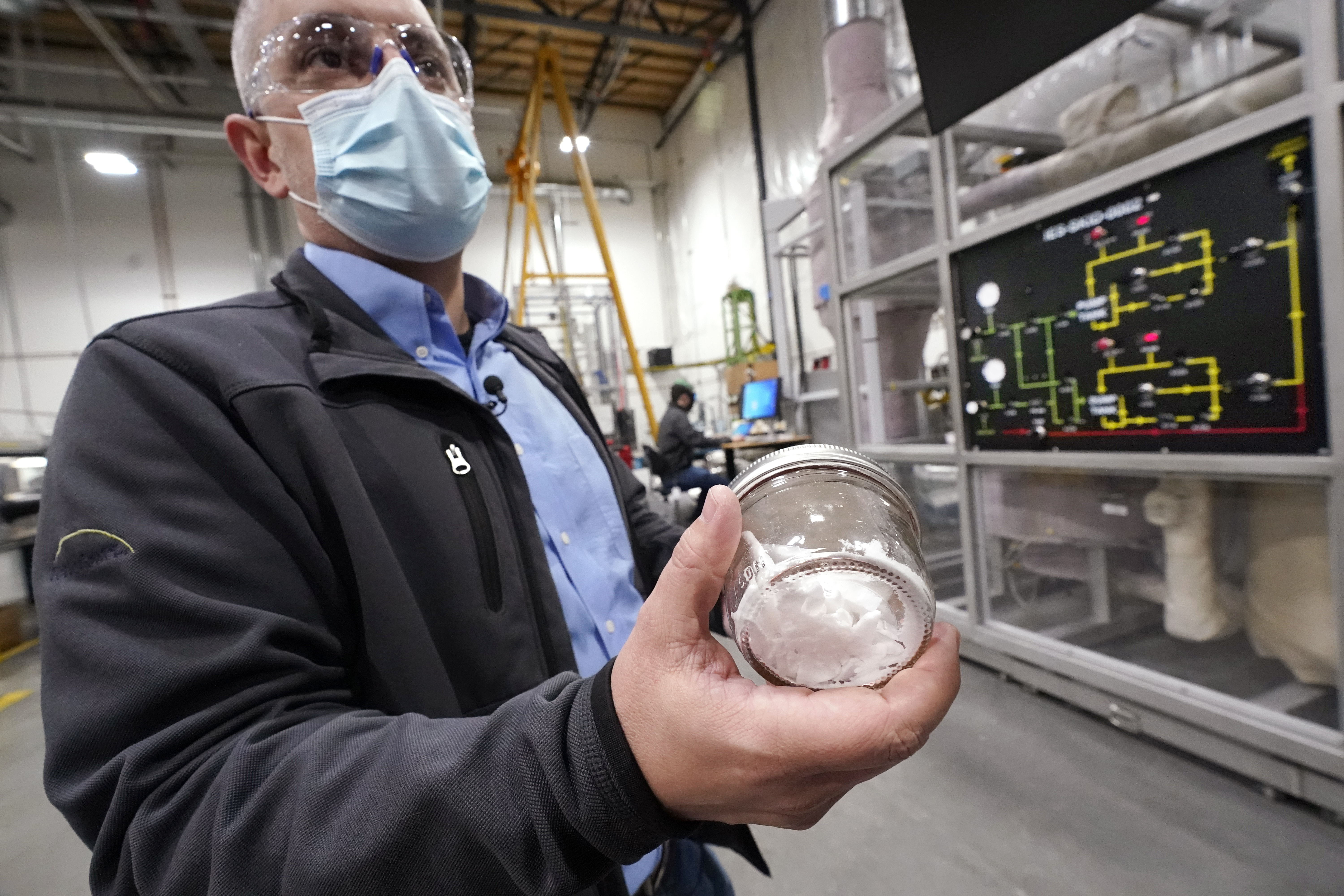 TerraPower's Michael Anderson, manager of test engineers and technicians, holds a glass jar holding purified salt during a tour of the nuclear reactor development facility, Thursday, Jan. 13, 2022, in Everett, Wash. TerraPower plans to make its plant useful for today's energy grid with ever more renewable power. A salt heat "battery" will allow a nuclear plant to ramp up electricity production on demand, offsetting dips in electricity when the wind isn't blowing and sun isn't shining.