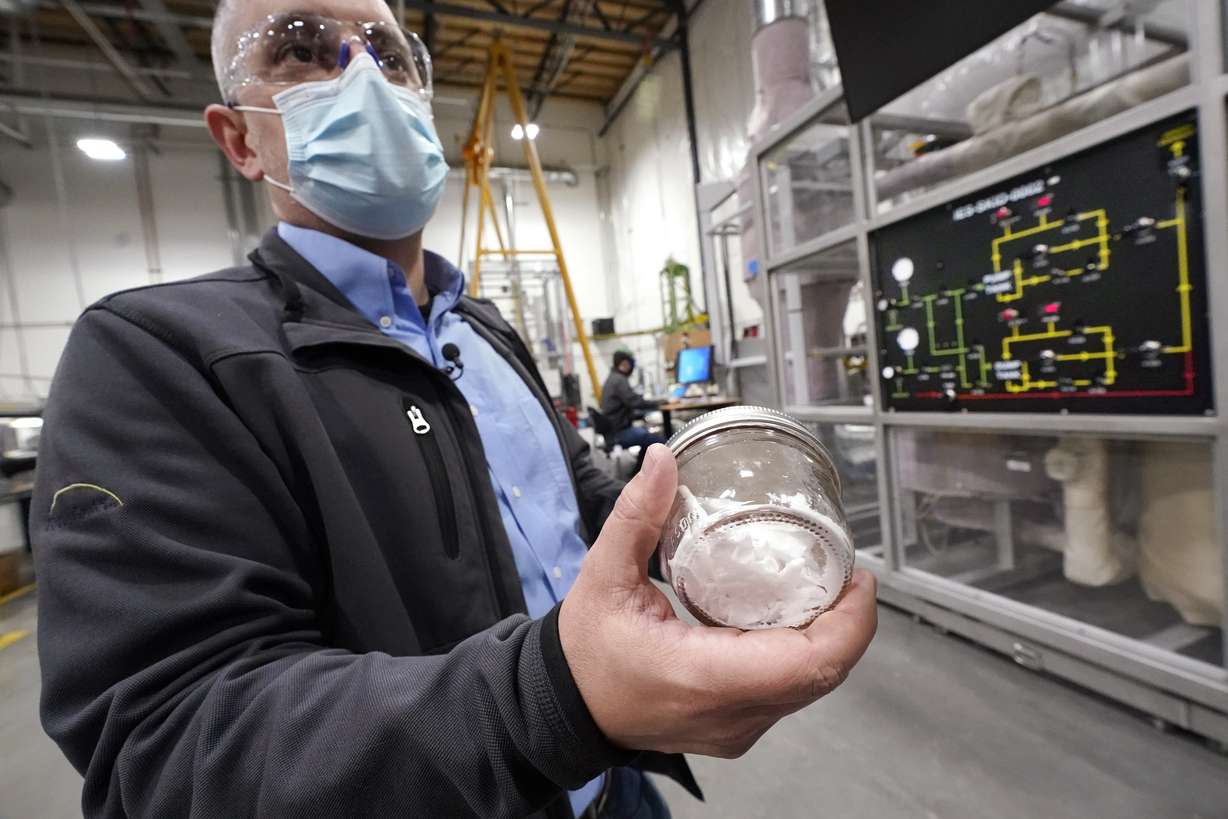TerraPower's Michael Anderson, manager of test engineers and technicians, holds a glass jar holding purified salt during a tour of the nuclear reactor development facility, Thursday, Jan. 13, 2022, in Everett, Wash. TerraPower plans to make its plant useful for today's energy grid with ever more renewable power. A salt heat "battery" will allow a nuclear plant to ramp up electricity production on demand, offsetting dips in electricity when the wind isn't blowing and sun isn't shining.