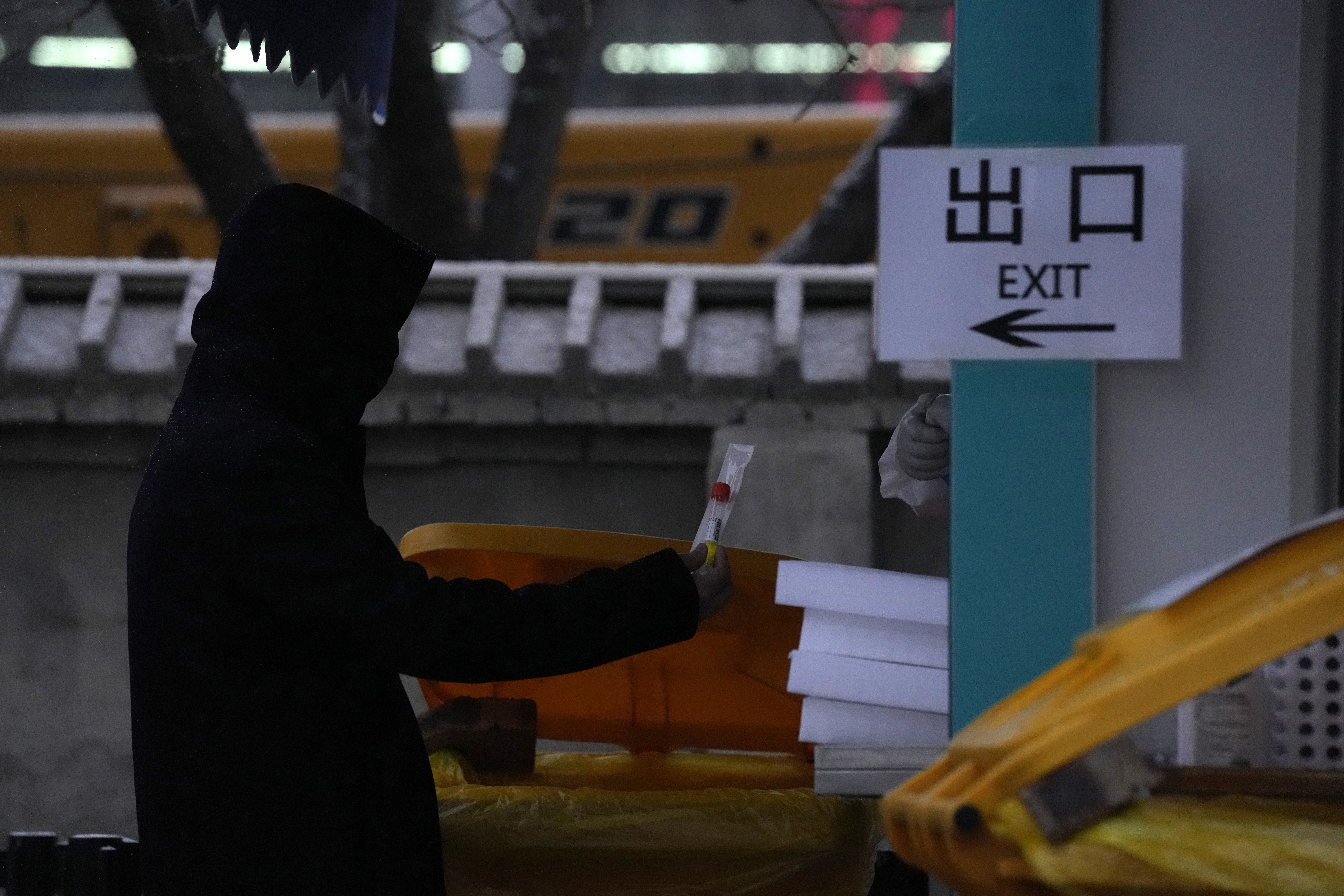 A resident holds up a tube and swab to get tested at a nuclei test station in Beijing, China, Friday, Jan. 21, 2022. The sweeping "zero-tolerance" policies that China has employed to protect its people and economy from COVID-19 may, paradoxically, make it harder for the country to exit the pandemic.