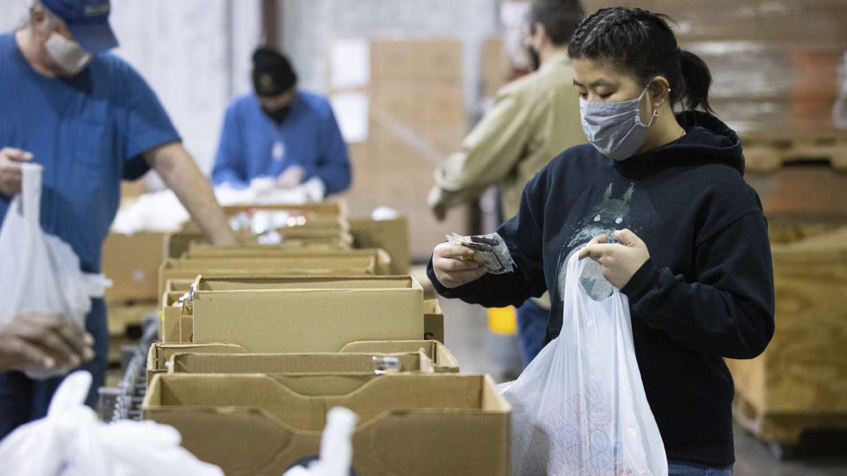 Volunteer Ana Willis fills a bag with food items for the backpack program at Feeding America food bank in Elizabethtown, Ky., Monday, Jan. 17, 2022. Food banks across the country are experiencing a critical shortage of volunteers as the omicron variant frightens people away from group activities.