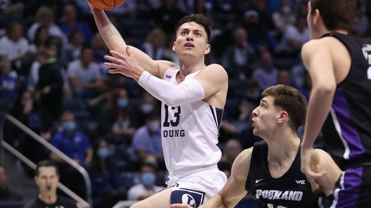 Brigham Young Cougars guard Alex Barcello (13) drives on Portland Pilots guard Matija Svetozarevic (13) in Provo on Saturday, Jan. 22, 2022.