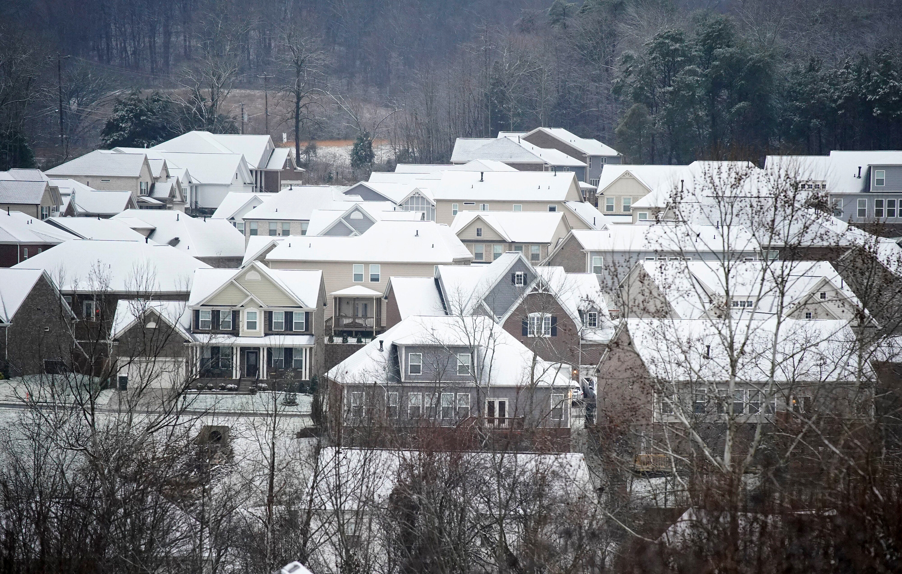 Winter storms and spiking energy prices could lead to record high heating bills. Snow and rain fall on rooftops of houses Sunday, Jan. 16, in Nashville, Tennessee.