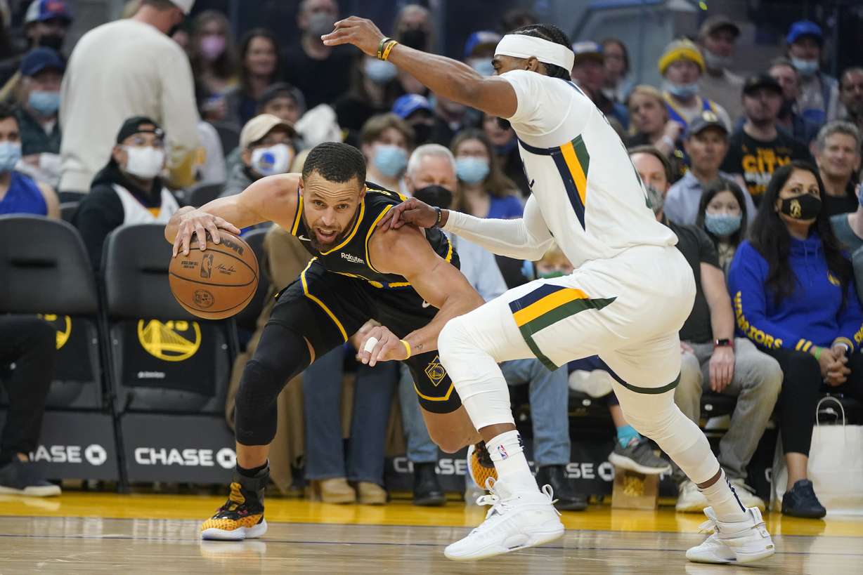 Golden State Warriors guard Stephen Curry, left, drives to the basket against Utah Jazz guard Mike Conley during the first half of an NBA basketball game in San Francisco, Sunday.