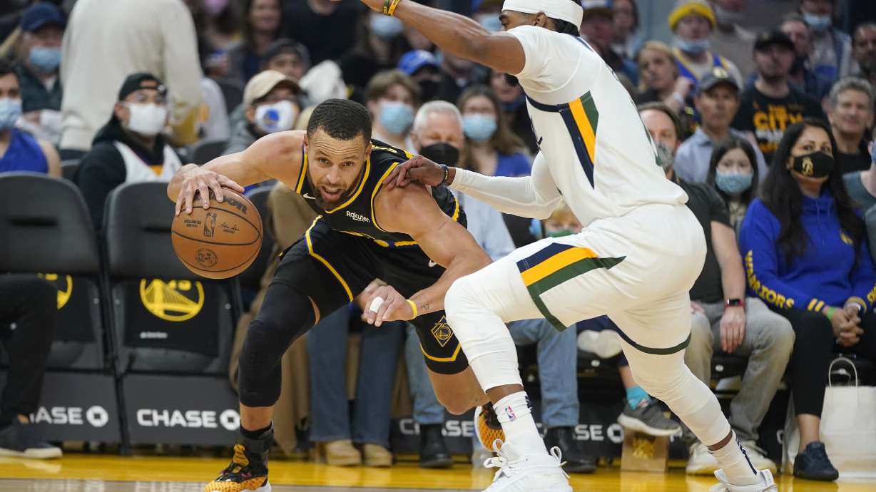 Golden State Warriors guard Stephen Curry, left, drives to the basket against Utah Jazz guard Mike Conley during the first half of an NBA basketball game in San Francisco, Sunday, Jan. 23, 2022.
