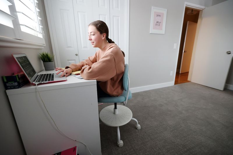Rachel Perry gives an answer to her teacher on her
computer as she and her sister, Charlotte Perry, participate in
school via their computers at home in Salt Lake City on Friday.