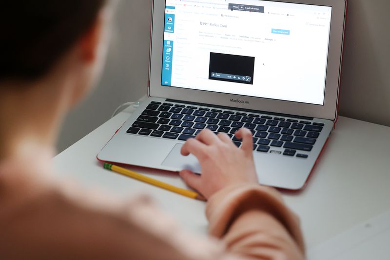 Rachel Perry moves to an assignment on her computer as
she and her sister, Charlotte Perry, participate in school via
their computers at home in Salt Lake City on Friday.