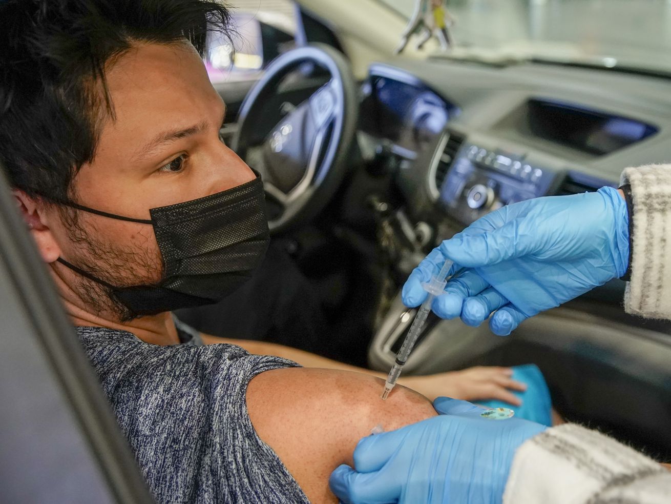 Ian Dominguez receives a COVID-19 booster shot from
registered nurse Emily Snow at a drive-thru vaccination clinic at
the Legacy Events Center in Farmington on Monday, Jan. 24, 2022.