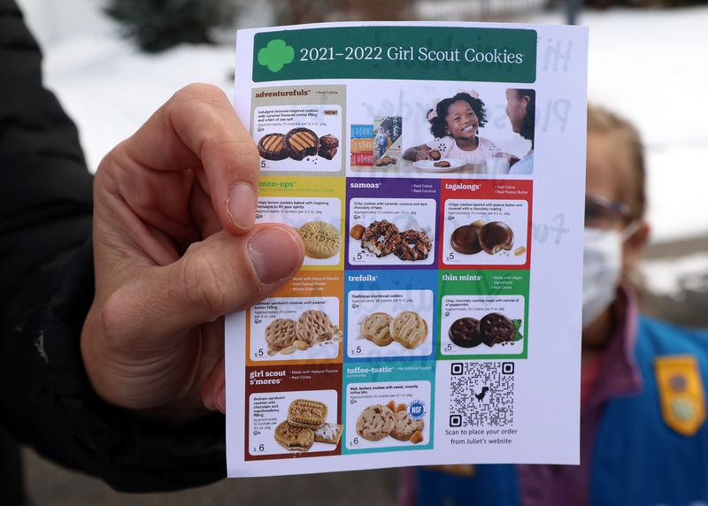 Kalie Agy shows a flyer she had printed to help people make their selections as she and her daughters Juliet and Annie go door-to-door selling Girl Scout Cookies in Cottonwood Heights on Tuesday.