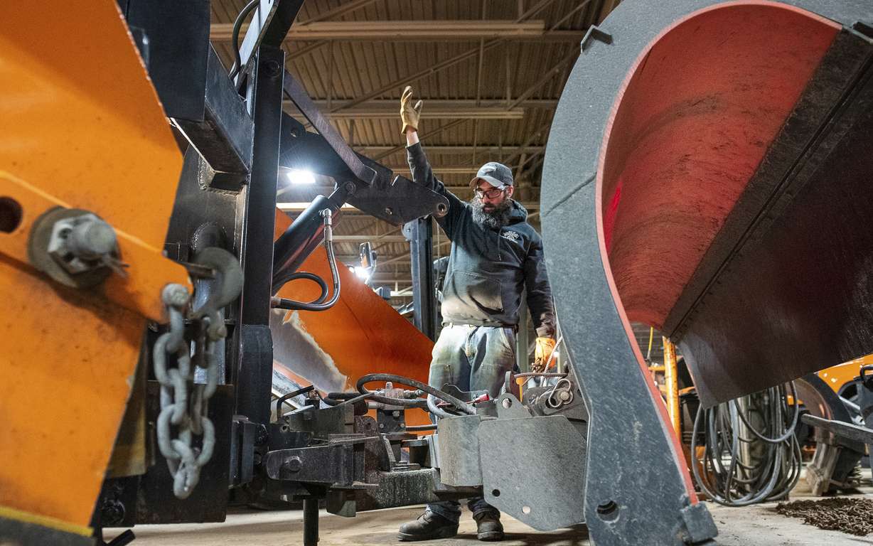 Auburn Public Works employee Andy Gagnon guides equipment operator Per Tripp as they attach the last blade to a truck in the Auburn, Maine, garage Friday morning, as they prepare for the weekend storm.