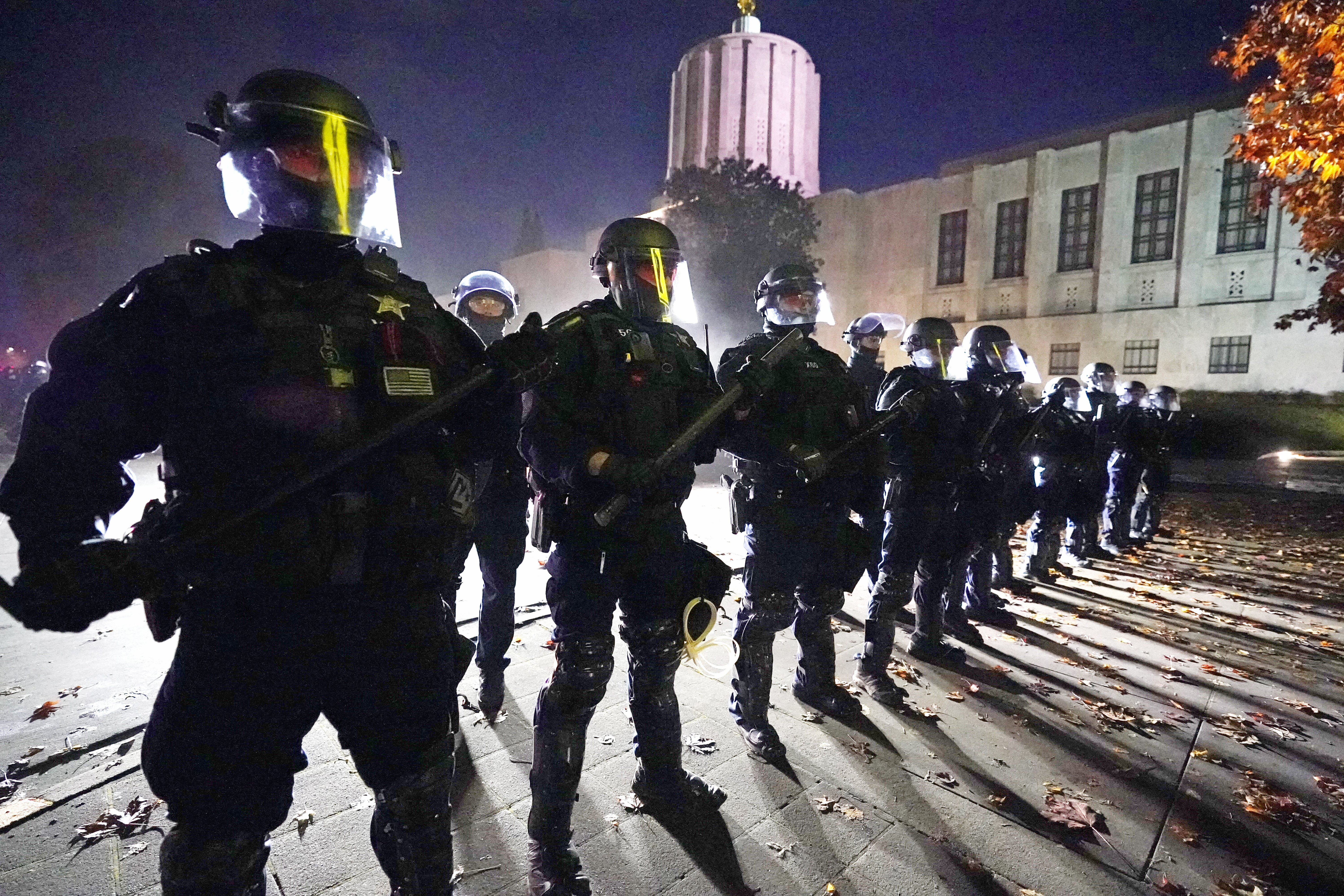 Police line up at the Oregon State Capitol building where demonstrators gathered Nov 7, 2020, in Salem, Ore. A civil rights trial against three former Minneapolis police officers seeks to hold them responsible for not stopping George Floyd's murder under Derek Chauvin's knee — and perhaps strike a blow against longstanding police culture that breeds reluctance to rein in fellow officers. 