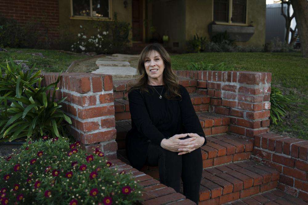 Jacki Graham, a 64-year-old COVID survivor, sits for a photo outside her home in Los Angeles, Thursday.