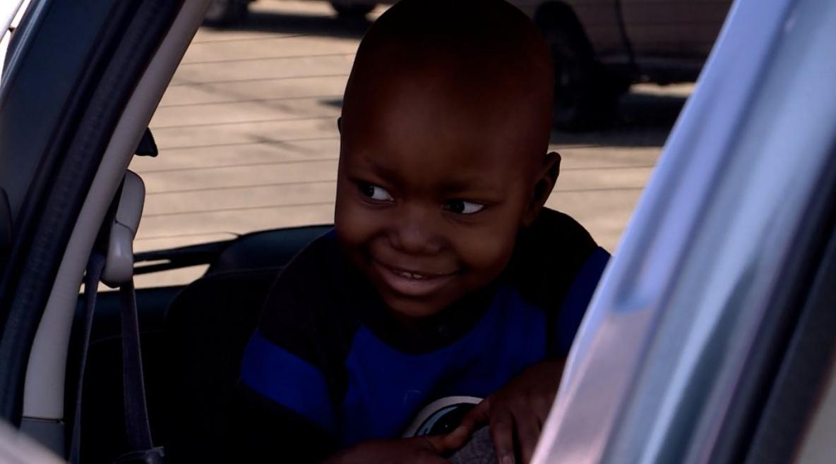 Nicholas Zchimpayi, age 3, sits in the car God's Garage provided for his family.
