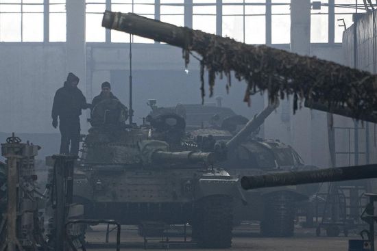 Workers stand atop a tank T-64 on Repair Tank Factory in Kharkiv, Ukraine, Monday.