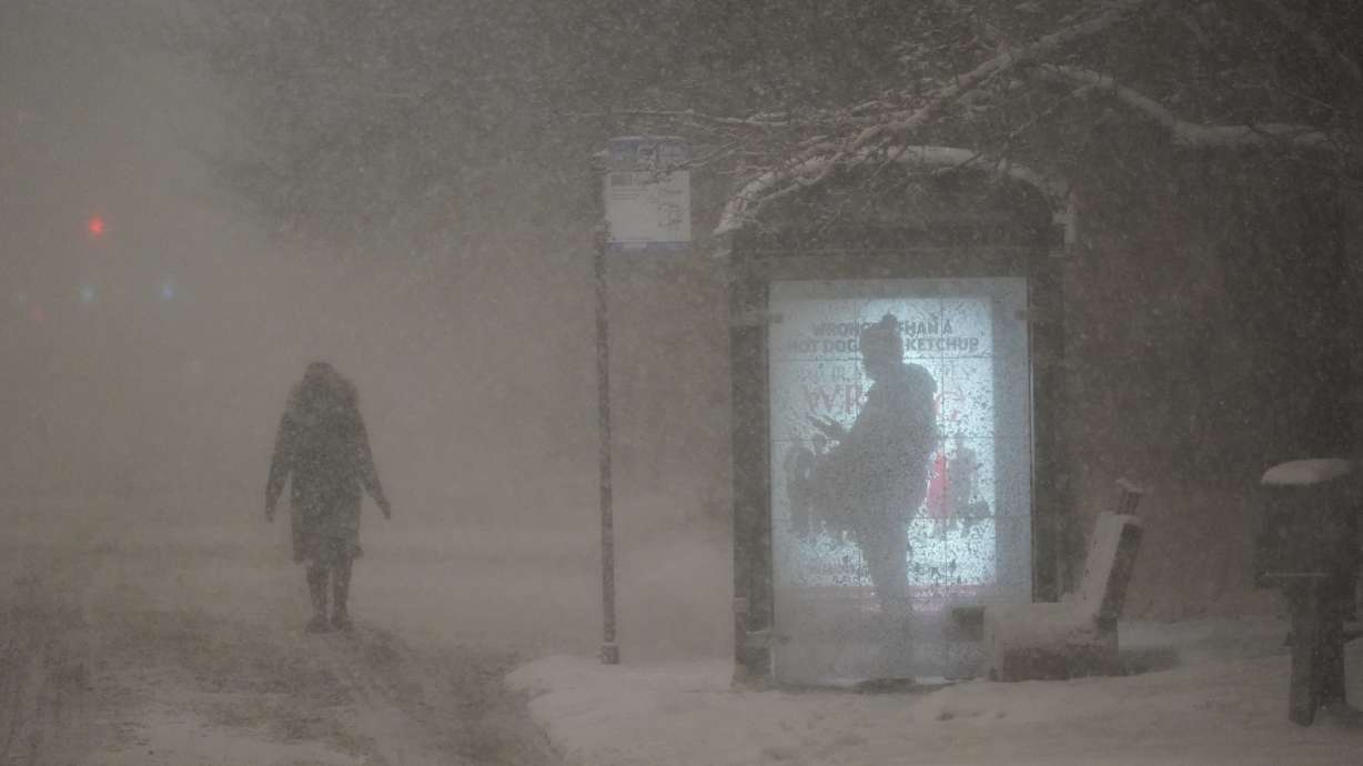 A woman walks to a bus shelter on Dr. Martin Luther King Drive as a man waits in the shelter during the pre-dawn hours Wednesday, in Chicago.