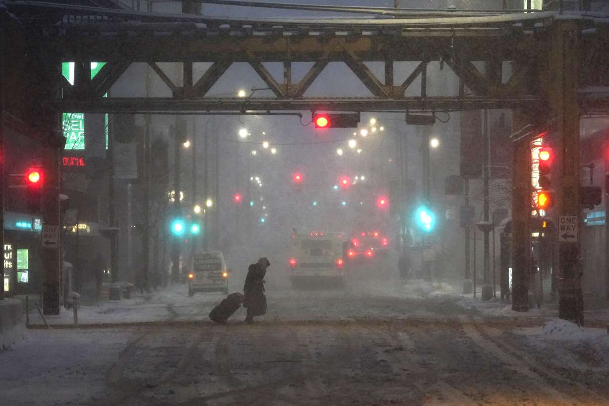 A lone pedestrian navigates Chicago's famed Loop in windy, falling snow and slushy street conditions Wednesday.