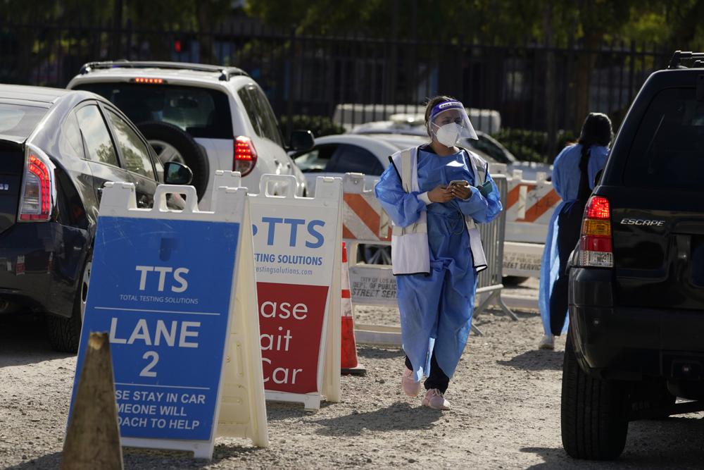 Workers wear protective equipment at a COVID-19 testing site Wednesday in the Boyle Heights section of Los Angeles. New cases of COVID-19 in the U.S. are falling in 49 of 50 states, even as the nation's death toll closes in on another bleak round number: 900,000.