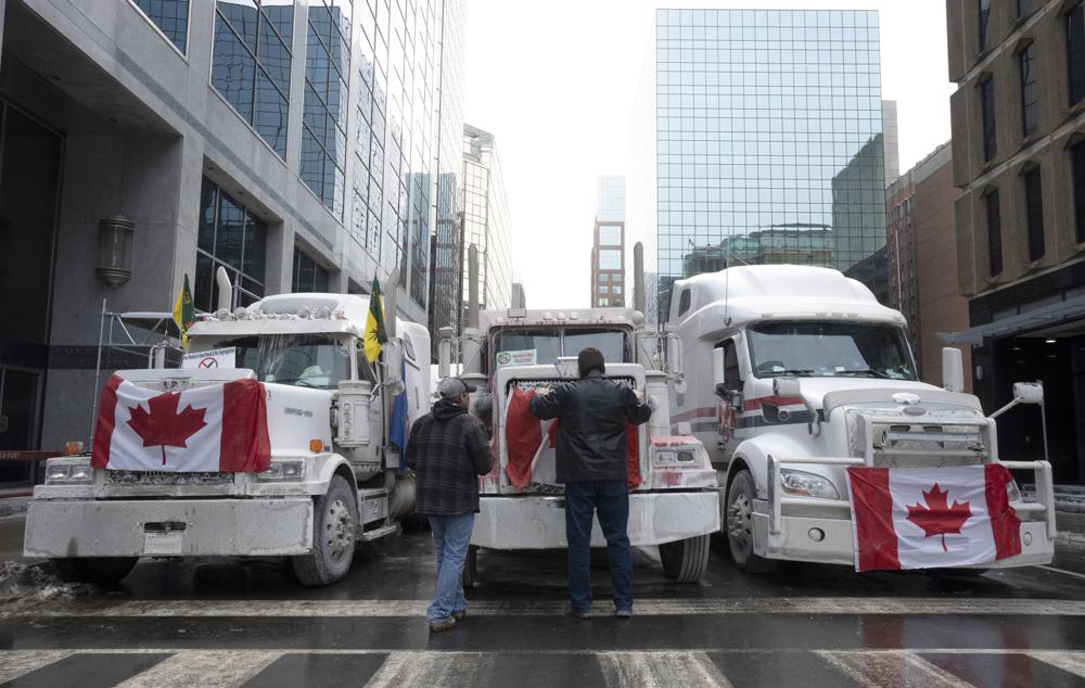 Truck drivers hang a Canadian flag on the front grill of a truck parked in downtown Ottawa, Ontario, near Parliament Hill on Wednesday. 