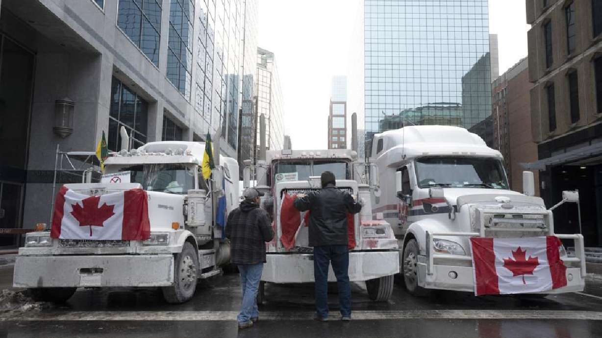 Truck drivers hang a Canadian flag on the front grill of a truck parked in downtown Ottawa, Ontario, near Parliament Hill on Wednesday.