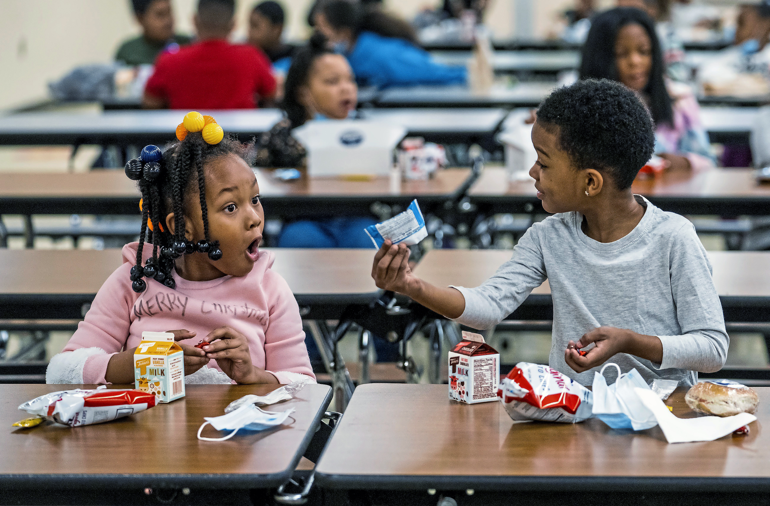 First graders, from left, Kendal Kates and Ryan Kenney are excited about the contents of their boxed lunches at Langley K-8 School, Dec. 23, in the Sheraden neighborhood in Pittsburgh. The Biden administration has issued transitional standards for school lunches that are meant to get cafeterias back on a healthier course as they recover from pandemic and supply chain disruptions.