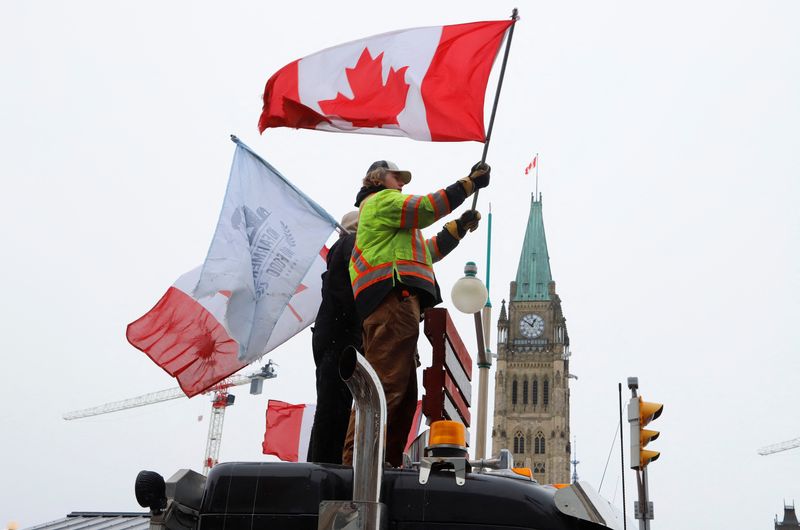 People wave flags on top of a truck in front of Parliament Hill as truckers and their supporters continue to protest against the COVID-19 vaccine mandates in Ottawa, Ontario, Canada, on Sunday.