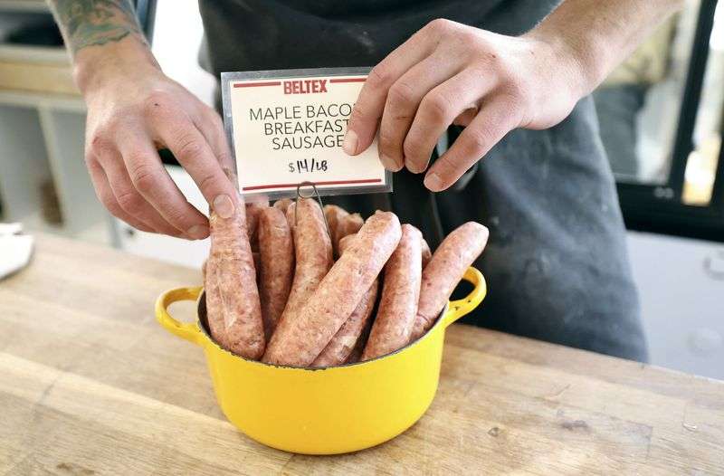 Chef Stephen Lott adds maple bacon breakfast sausages
to a display case at Beltex Meats in Salt Lake City on Friday.