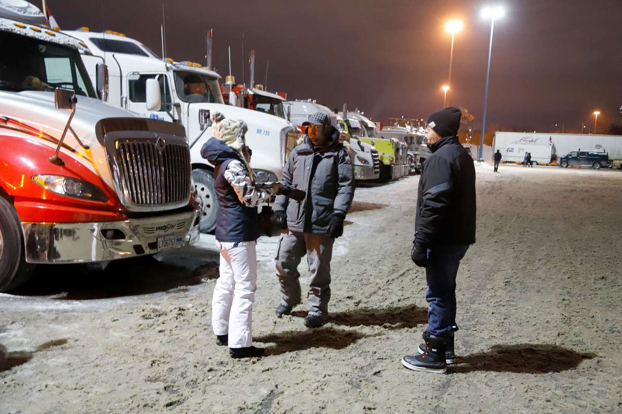 People stand in a staging area east of downtown after police raided the truckers' stockpile of fuel, as truckers and their supporters continue to protest against coronavirus disease vaccine mandates, in Ottawa, Ontario, Canada, Sunday.