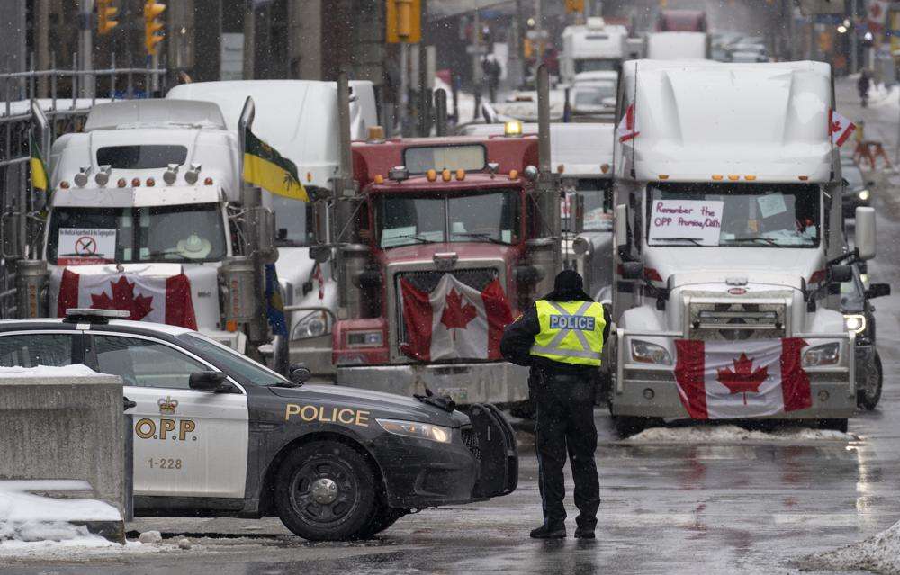 Police man a barricade in front of vehicles parked as part of the trucker protest, Tuesday, in Ottawa's downtown core.