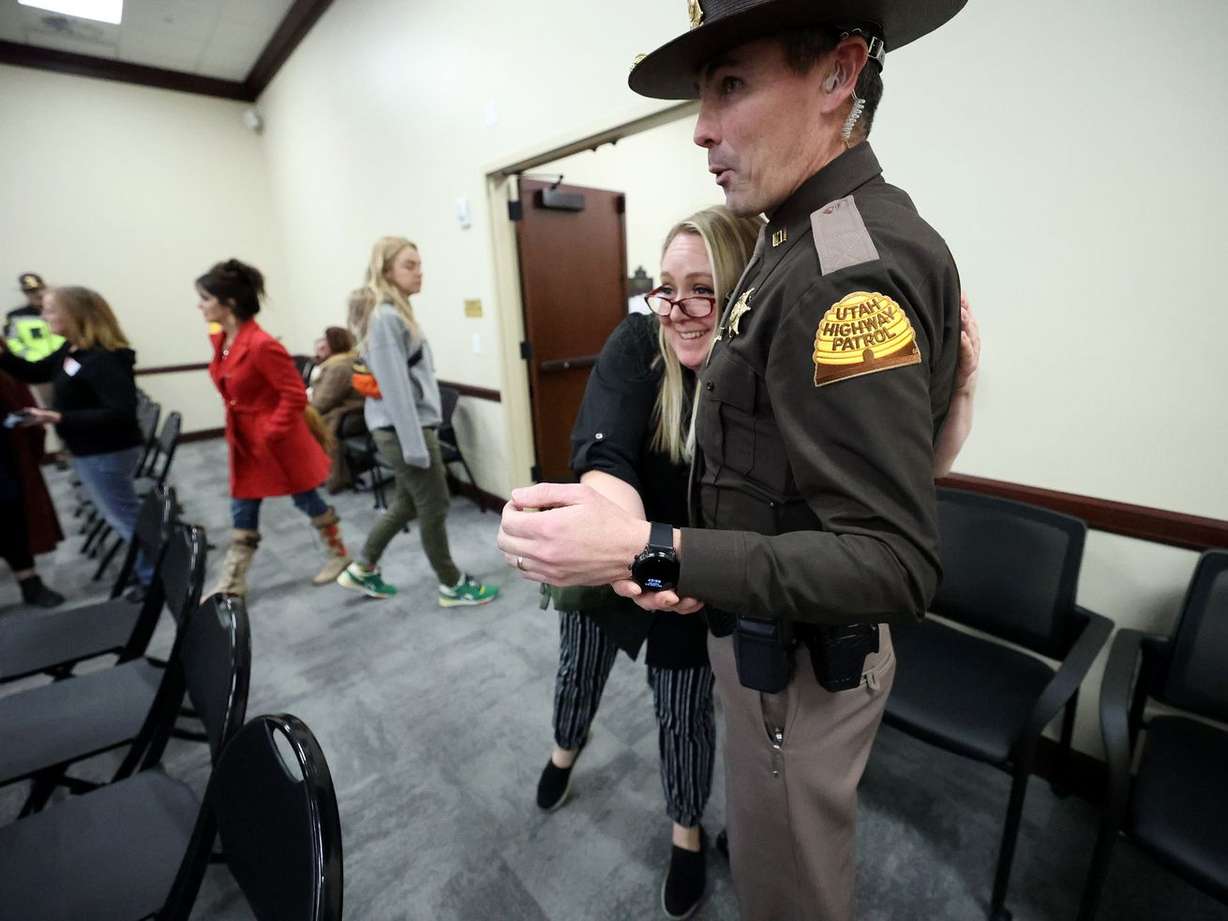 A woman hugs a UHP trooper after SB88 was held after
residents showed up to express feelings on digital driver license
amendments in the House Public Utilities, Energy and Technology
Committee hearing in the Senate building at the Capitol in Salt
Lake City on Monday.