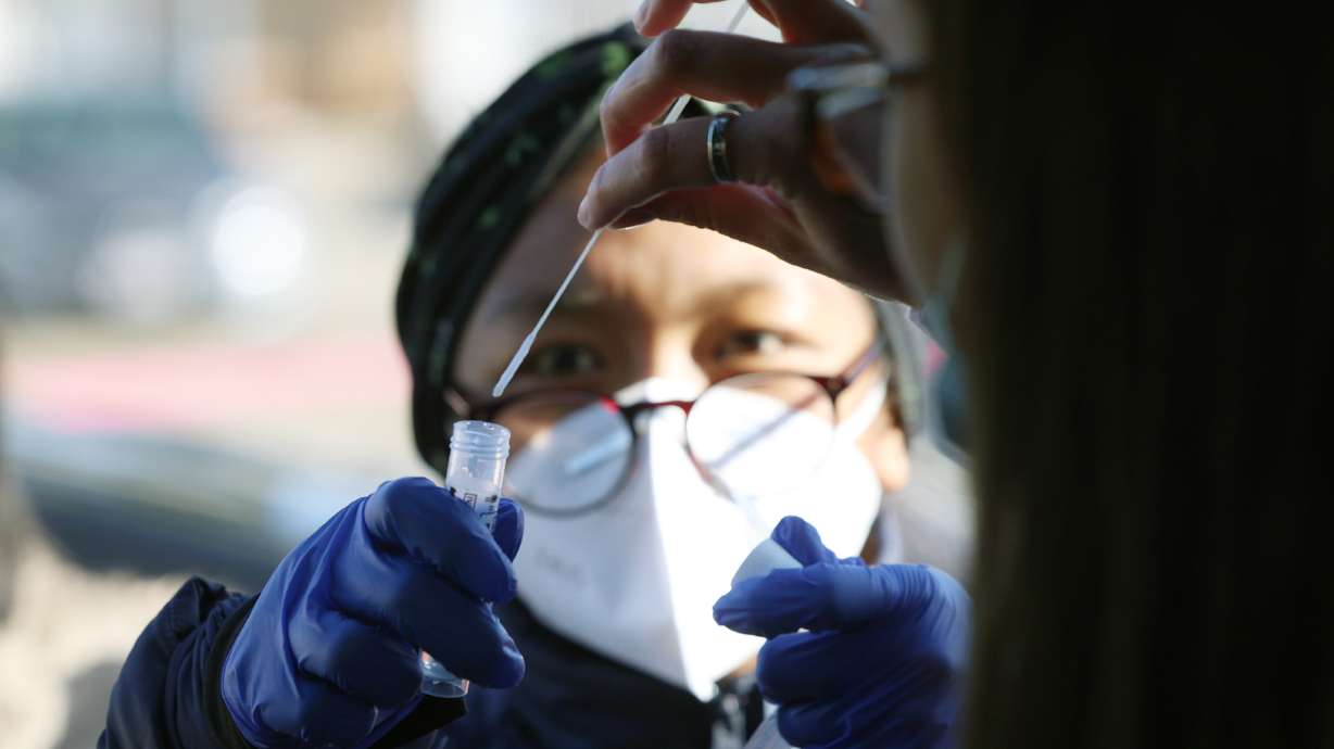 Caiden Bishop places her COVID-19 swab into a vial held by registered nurse Emily Mateo at the University of Utah in Salt Lake City on Jan. 31. Utah announced a pause of a rapid antigen test following a review of 18,000 cases. The manufacturer of those tests said Wednesday they stand by their product.