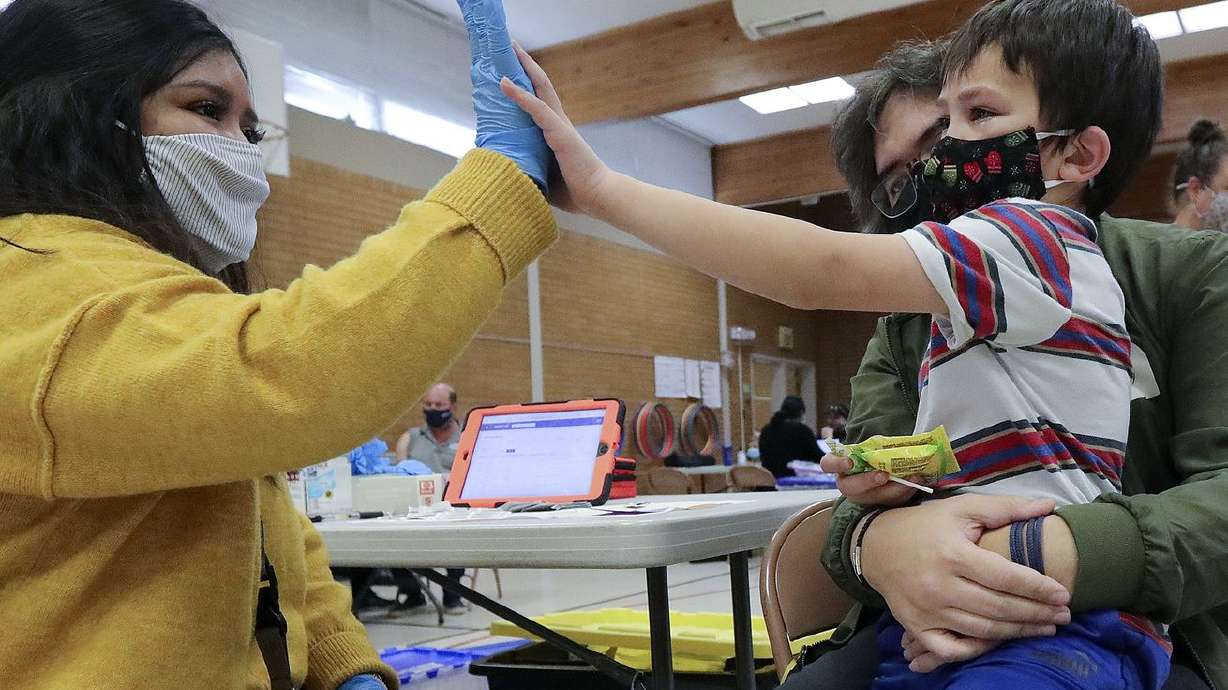 Claudia Ceron, a Salt Lake County Health Department community health worker and vaccinator, high-fives kindergartner Eddie Purcell after he received a COVID-19 vaccination at Hillsdale Elementary School in West Valley City on Nov. 8, 2021.