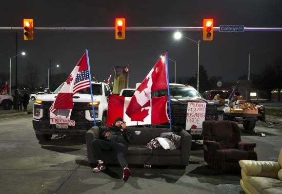 A trucker supporter sits on a couch as they block the access leading from the Ambassador Bridge, linking Detroit and Windsor, to protest against the COVID-19 vaccine mandates and restrictions, Wednesday.