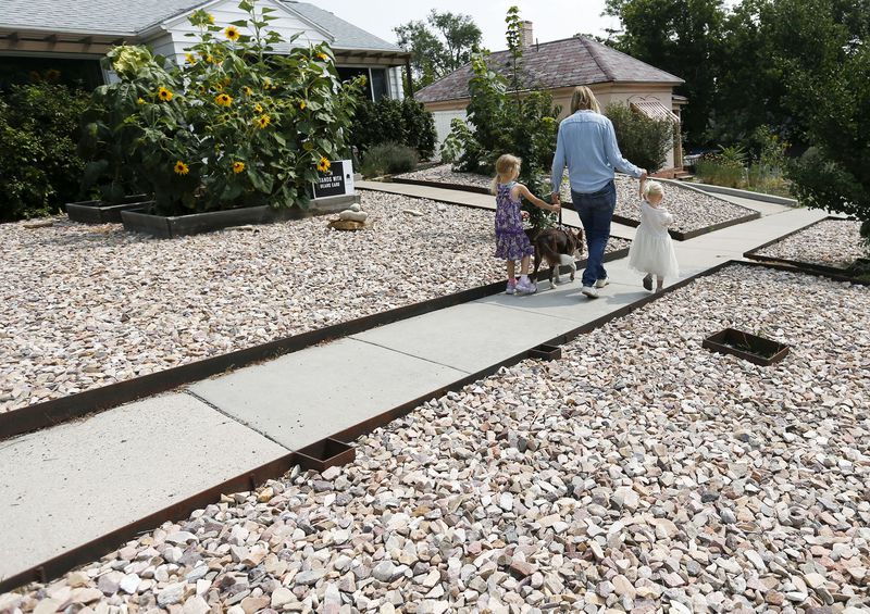 Rachel Simeon and her daughters, Ela and Yara, walk in
front of their Salt Lake City home on Aug. 20, 2021. Simeon says
she was dumbfounded when she got a letter from Salt Lake City code
enforcement, in the midst of Utah’s historic drought, that she
needed to add more vegetation to her park strip, which would
require more water.