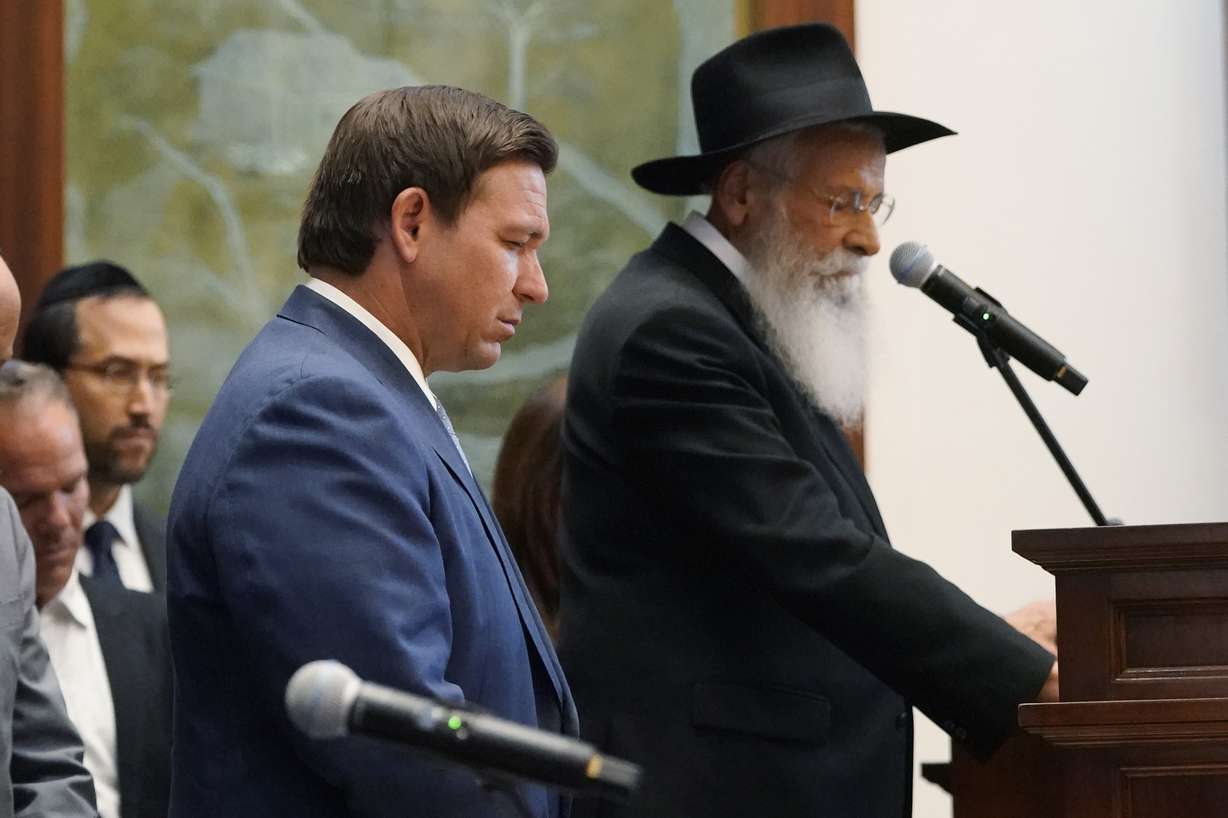 Rabbi Sholom Lipskar, Florida Gov. Ron DeSantis, left, and others participate in a moment of silence, Monday, June 14, 2021, at the Shul of Bal Harbour, a Jewish community center in Surfside, Fla. Lipskar says he tells congregation members that COVID-19 vaccination should be a matter of free choice.