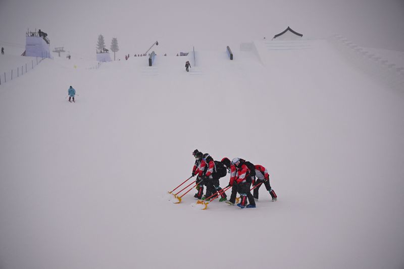 2022 Beijing Olympics - Freestyle Skiing - Women's Freeski Slopestyle - Qualification - Run 1 - Genting Snow Park, Zhangjiakou, China - February 13, 2022.   Workers clear the course as the start is delayed.
