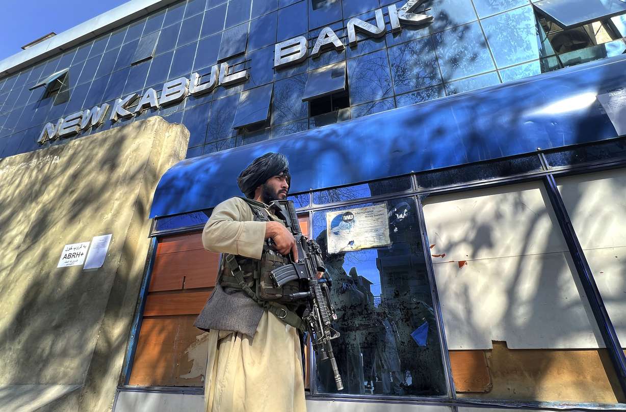 Taliban fighters stand guards outside a bank, in Kabul, Afghanistan, Sunday. Afghanistan's former president Hamid Karzai called a White House order freeing $3.5 billion in Afghan assets for America's 9/11 families "an atrocity against the Afghan people."
