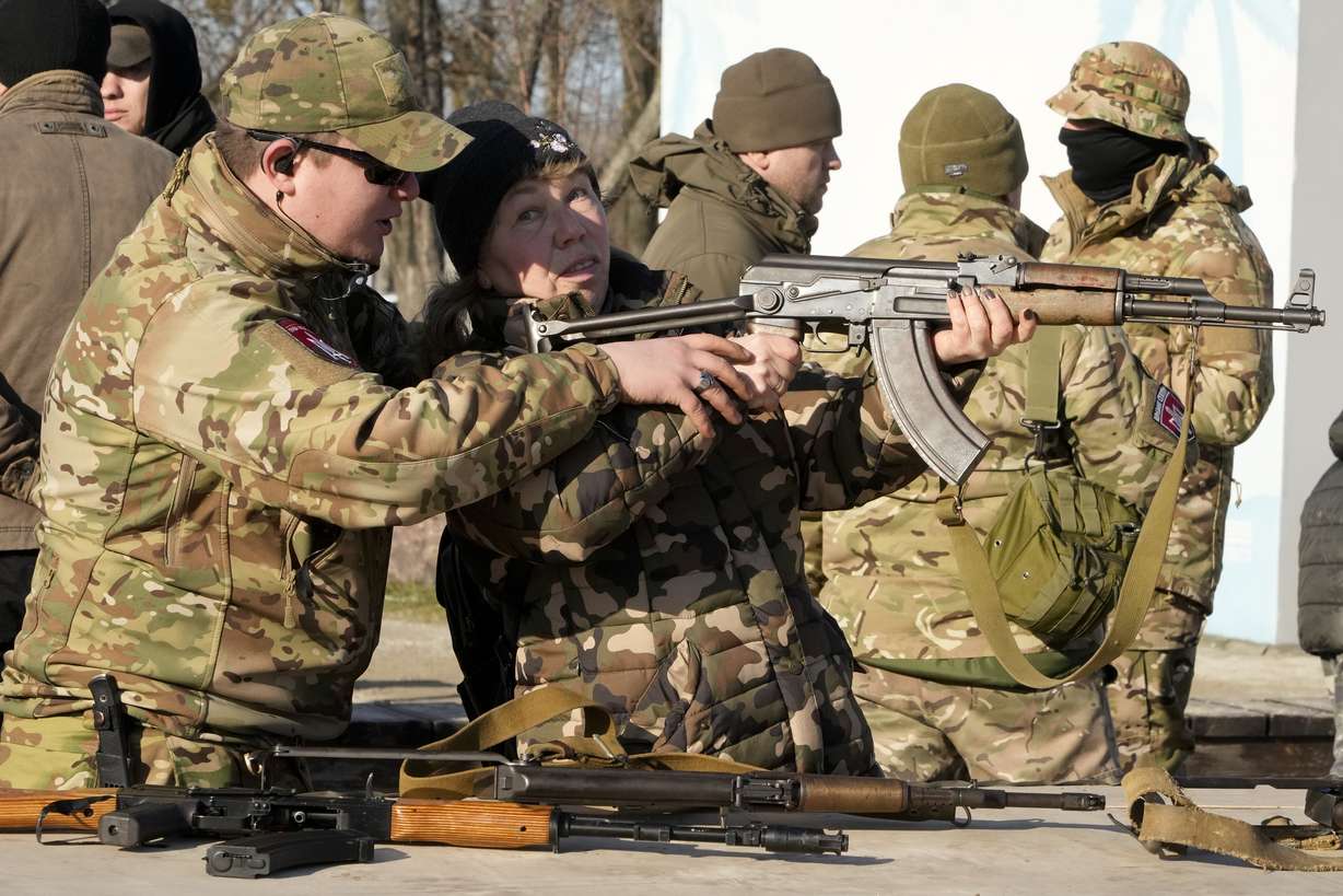 An instructor shows a woman how to use a Kalashnikov assault rifle, as members of a Ukrainian far-right group train, in Kyiv, Ukraine, Sunday. Russia denies it intends to invade but has massed well over 100,000 troops near the Ukrainian border and has sent troops to exercises in neighboring Belarus, encircling Ukraine on three sides. U.S. officials say Russia's buildup of firepower has reached the point where it could invade on short notice.