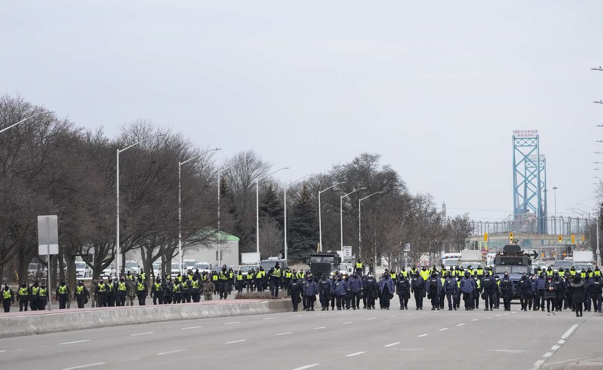 Police walk the line to remove all truckers and supporters after a court injunction gave police the power to enforce the law after protesters blocked the access leading from the Ambassador Bridge, linking Detroit and Windsor, as truckers and their supporters continue to protest against COVID-19 vaccine mandates and restrictions, in Windsor, Ontario, Sunday.