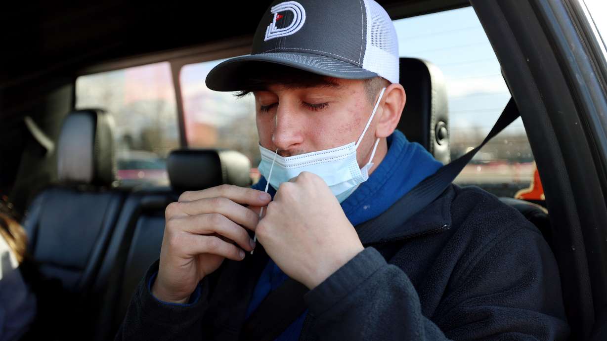 Nathan Graham tries not to sneeze as he swabs his nose for a COVID-19 test at the University of Utah in Salt Lake City on Jan. 31. Utah reported over 3,000 new COVID-19 cases on Monday and 39 deaths.