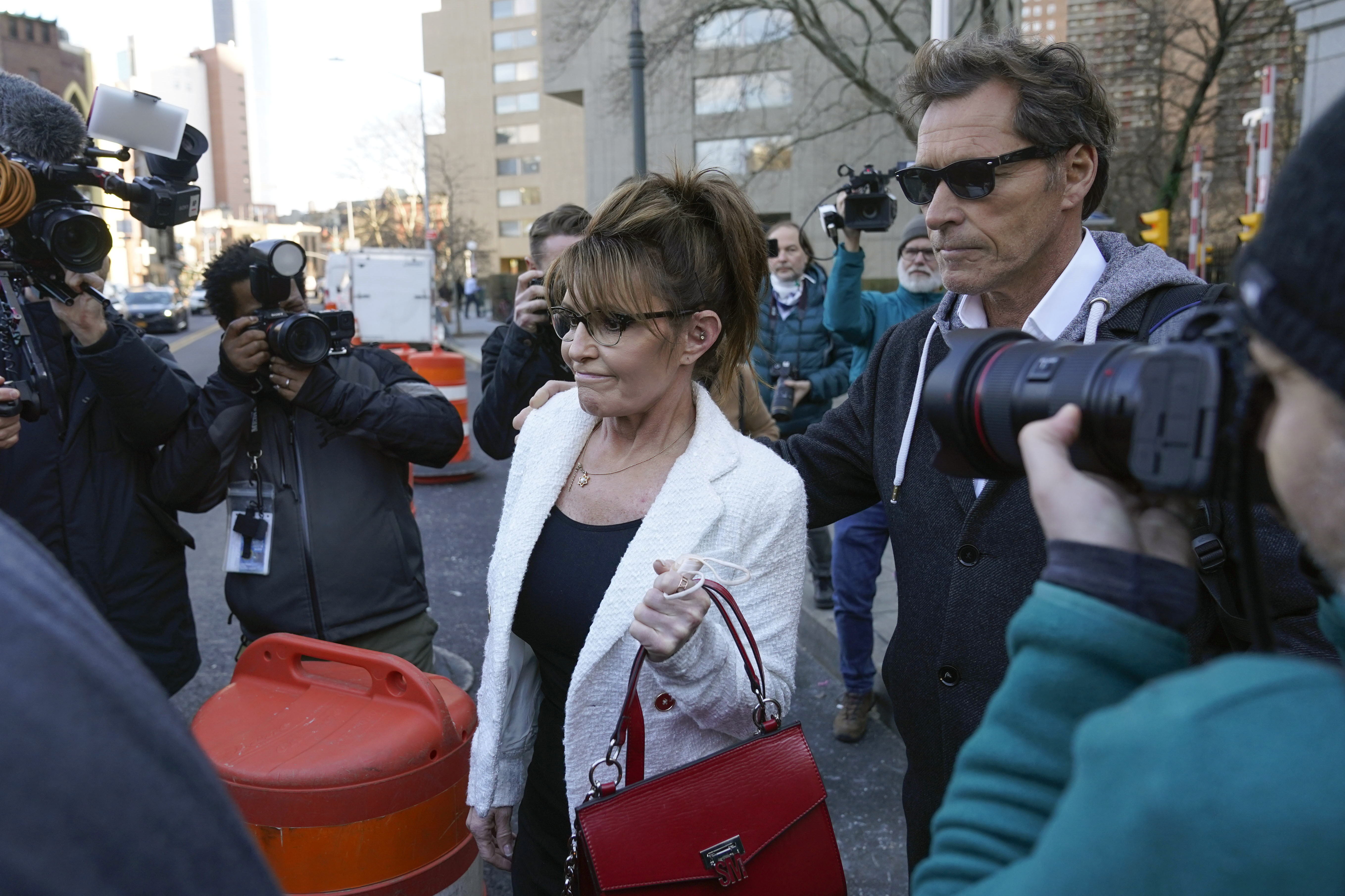 Former Alaska Gov. Sarah Palin is escorted to her car by Ron Duguay after leaving the courthouse in New York, on Feb. 10. A judge said Monday he'll dismiss a libel lawsuit that Palin filed against The New York Times.