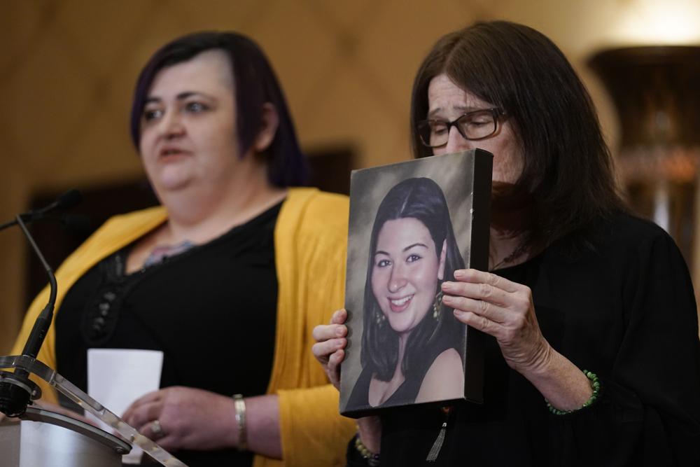While Hannah D'Avino, left, speaks, Mary D'Avino holds up a picture of her daughter Rachel D'Avino, who was killed during the Newtown shooting, during a news conference in Trumbull, Conn., Tuesday. The families of nine victims of the Sandy Hook Elementary School shooting have agreed to a $73 million settlement of a lawsuit against the maker of the rifle used to kill 20 first graders and six educators in 2012, their attorney said Tuesday.