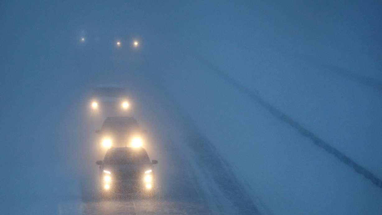 Headlights from morning commuters can be seen through blowing snow Jan. 28, 2019, in Appleton, Wis., regulators are about to allow new high-tech headlights that can automatically tailor beams so they focus on dark areas of the road and don't create glare for oncoming drivers.
