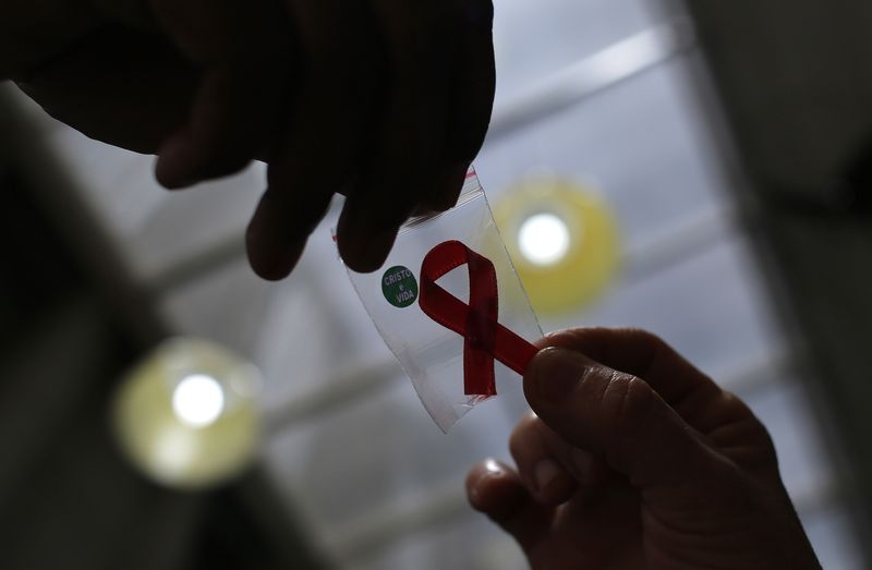A nurse hands out a red ribbon to a woman to mark World Aids Day, at the entrance of Emilio Ribas Hospital, in Sao Paulo Dec. 1, 2014.