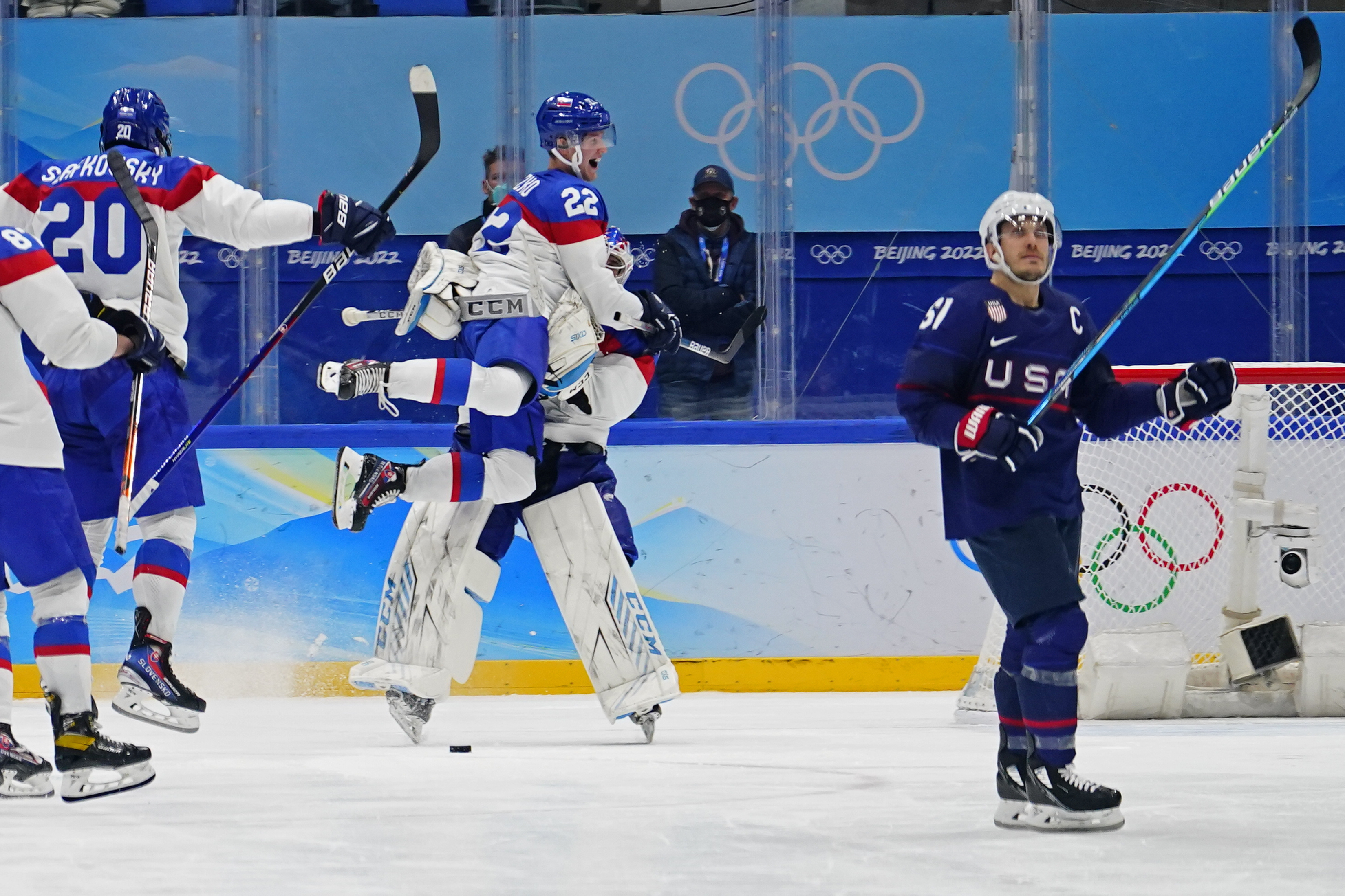 Slovakia's Samuel Knazko (22) jumps onto goalkeeper Patrik Rybar after Rybar blocked the final shoot-out attempt by United States' Andy Miele, right, during a men's quarterfinal hockey game at the 2022 Winter Olympics, Wednesday, Feb. 16, 2022, in Beijing. Slovakia won 3-2.