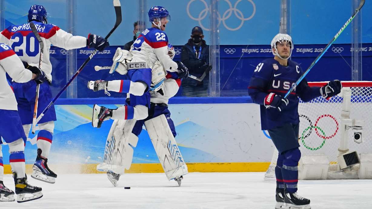 Slovakia's Samuel Knazko (22) jumps onto goalkeeper Patrik Rybar after Rybar blocked the final shoot-out attempt by United States' Andy Miele, right, during a men's quarterfinal hockey game at the 2022 Winter Olympics, Wednesday, Feb. 16, 2022, in Beijing. Slovakia won 3-2.