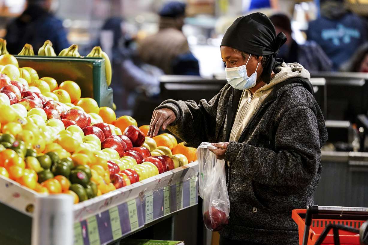 A shopper wearing a proactive mask selects fruit at the Reading Terminal Market in Philadelphia, Wednesday. Philadelphia city officials lifted the city's vaccine mandate for indoor dining and other establishments that serve food and drinks, but an indoor mask mandate remains in place. Philadelphia Public Health officials announced that the vaccine mandate was lifted immediately Wednesday.