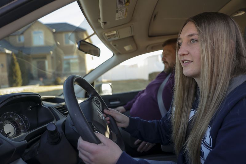 Ally Brewer, front, drives her new car with her dad,
West Brewer, around the neighborhood in Herriman on Friday, Feb.
11.