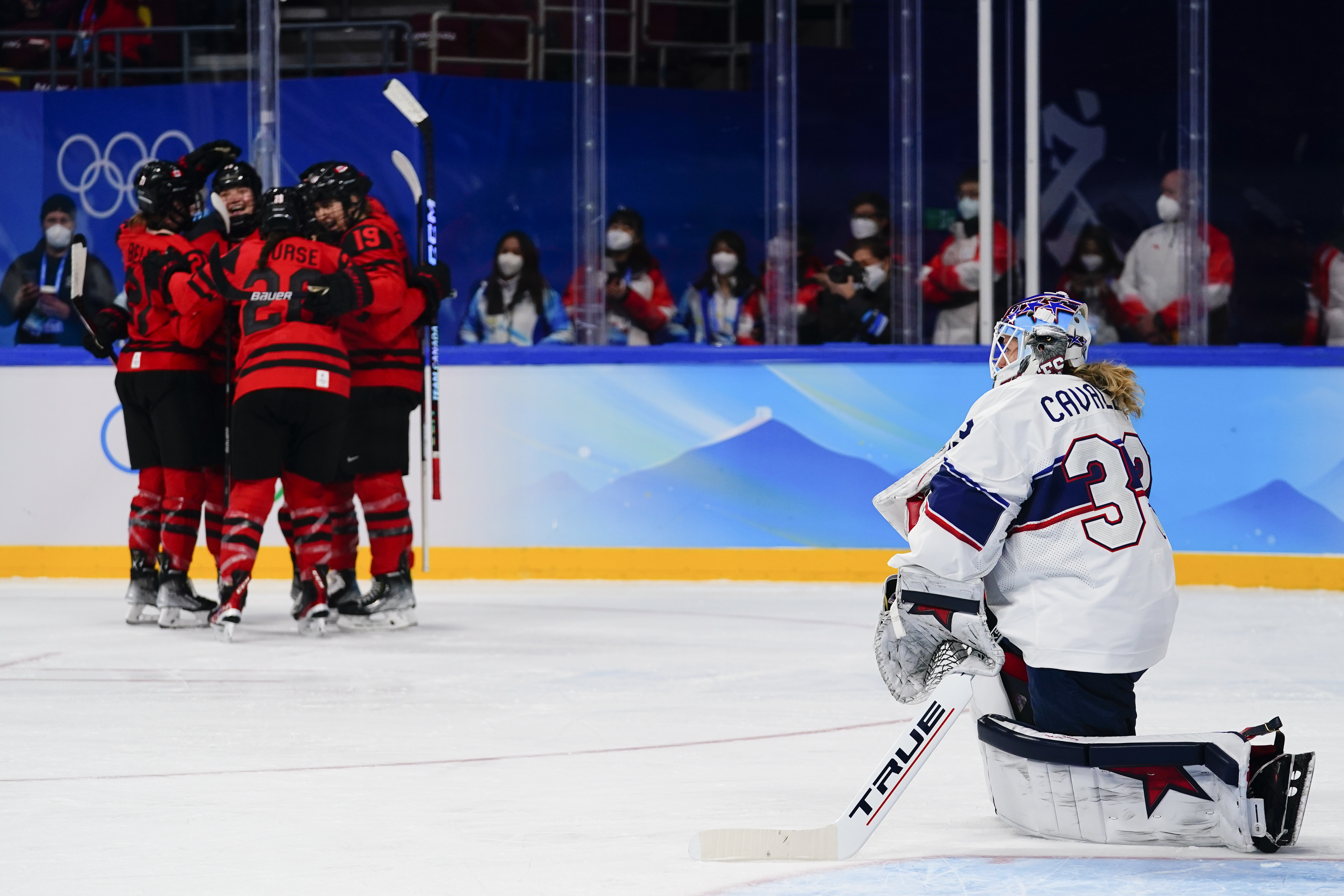 United States goalkeeper Alex Cavallini (33) kneels on the ice as Canada players celebrate after a goal by Marie-Philip Poulin during the women's gold medal hockey game at the 2022 Winter Olympics, Thursday, Feb. 17, 2022, in Beijing. 