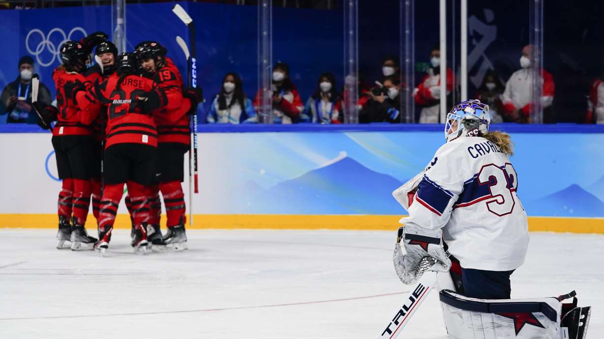 United States goalkeeper Alex Cavallini (33) kneels on the ice as Canada players celebrate after a goal by Marie-Philip Poulin during the women's gold medal hockey game at the 2022 Winter Olympics, Thursday, Feb. 17, 2022, in Beijing.